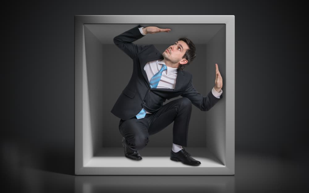 Young businessman trapped inside uncomfortable small box.