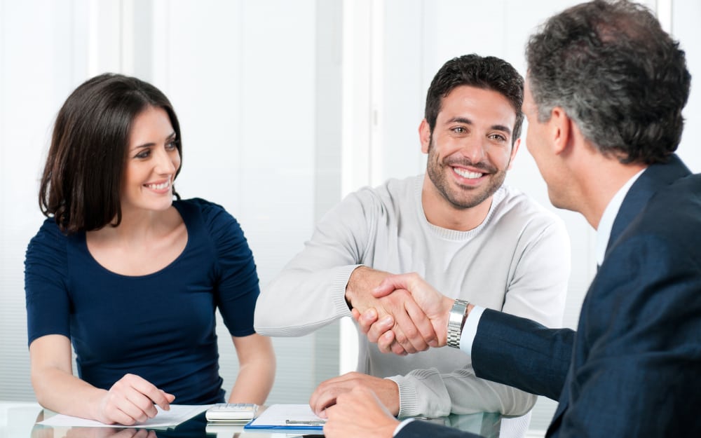 Happy couple seal a deal with their personal financial advisor at home