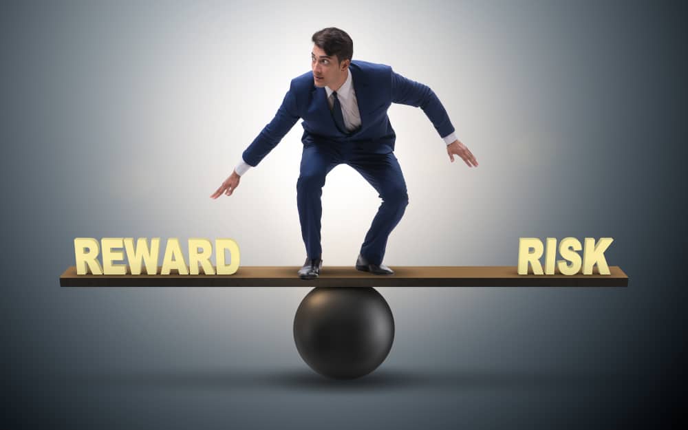 Businessman balancing between reward and risk business concept