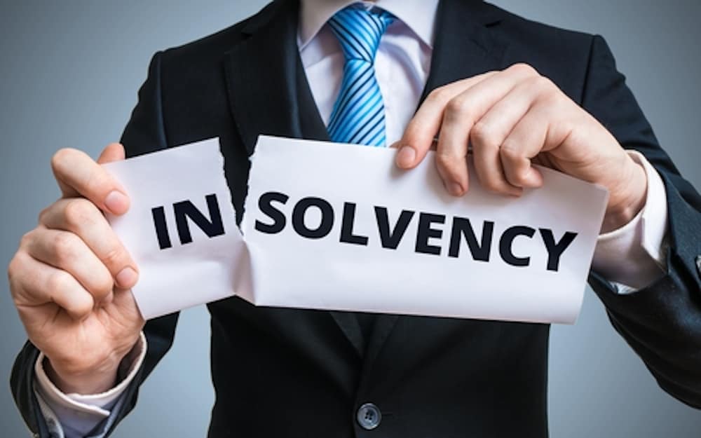 a guy wearing suit holding a torn paper with Insolvency word written